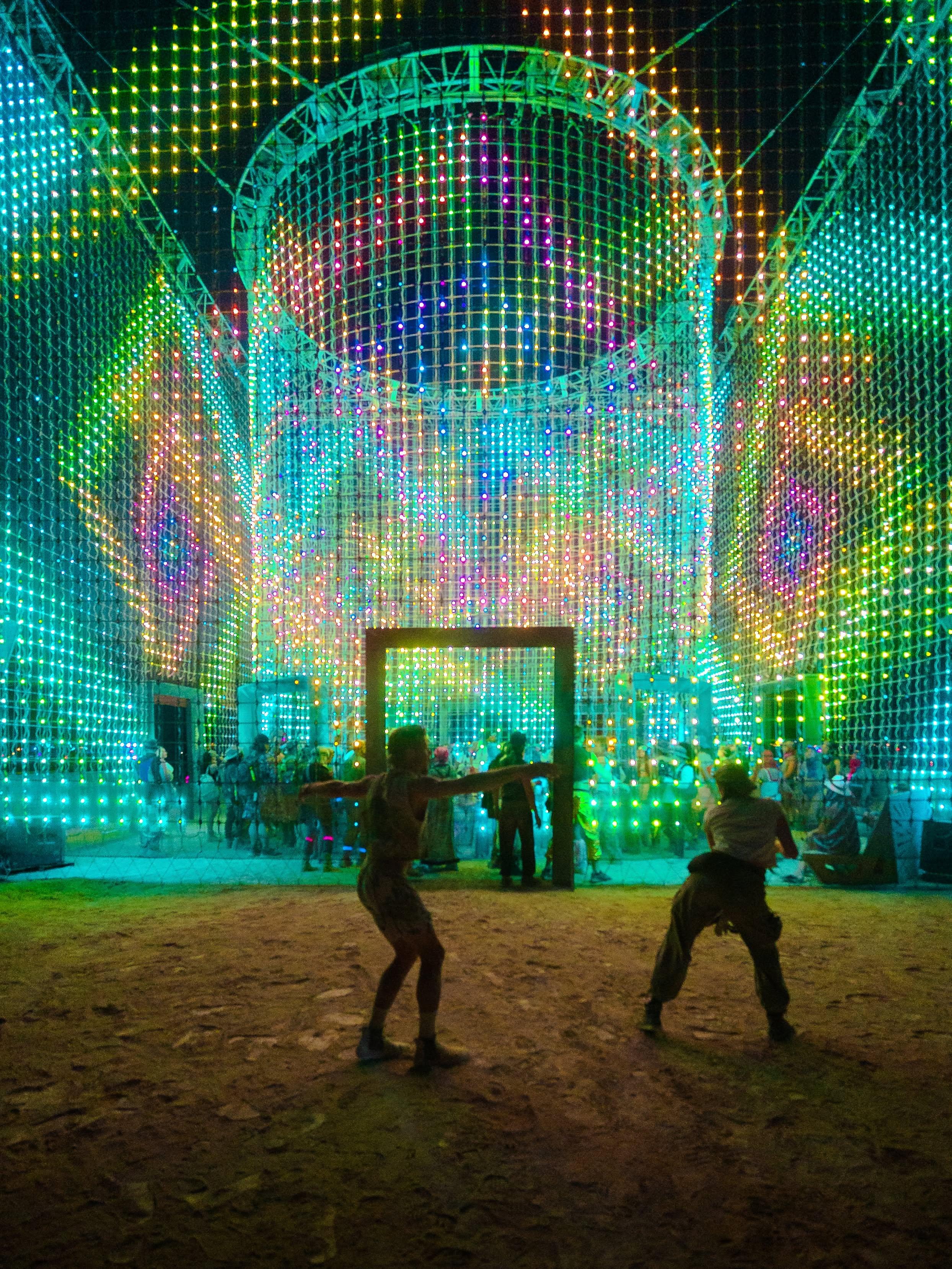 People dancing in front of Apotheneum's illuminated structure
